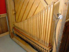 The pipe chest and two ranks of pipes installed inside back. The violins show, with the stopped flutes hiding between them and the soundboard. The massive piano cabinet and plate provide support for the string tension without the usual back posts.